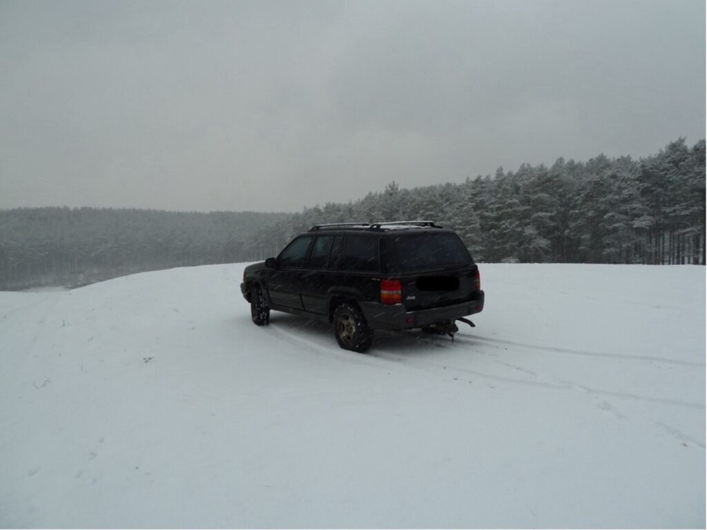 A black Jeep driving on a snowy hill