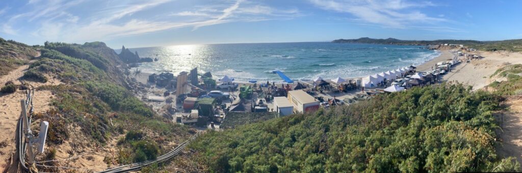 A panoramic photo of a film crew on a beach in Sardinia